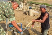 Caption : Salah seorang anggota TNI sedang mengecek air dari sumur bor