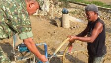 Caption : Salah seorang anggota TNI sedang mengecek air dari sumur bor