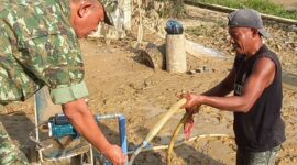 Caption : Salah seorang anggota TNI sedang mengecek air dari sumur bor